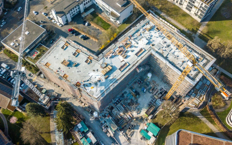 Blick von oben auf ein grosses Gebäude, das sich im Bau befindet. Baustelle