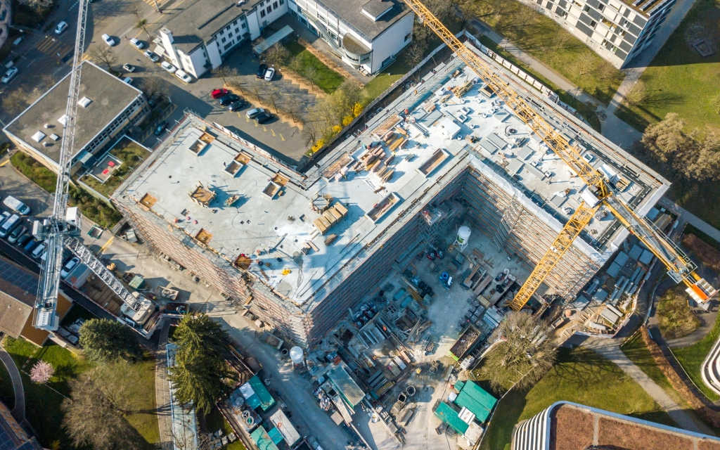 Blick von oben auf ein grosses Gebäude, das sich im Bau befindet. Baustelle