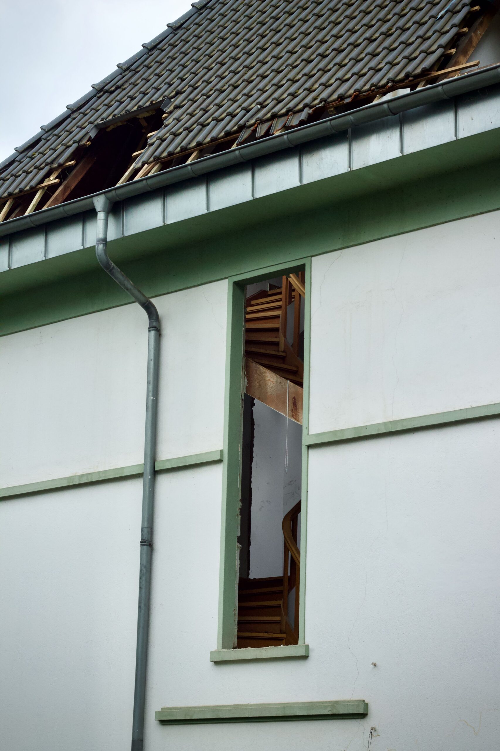 Haus mit beschädigtem Ziegeldach und beschädigtem Fenster