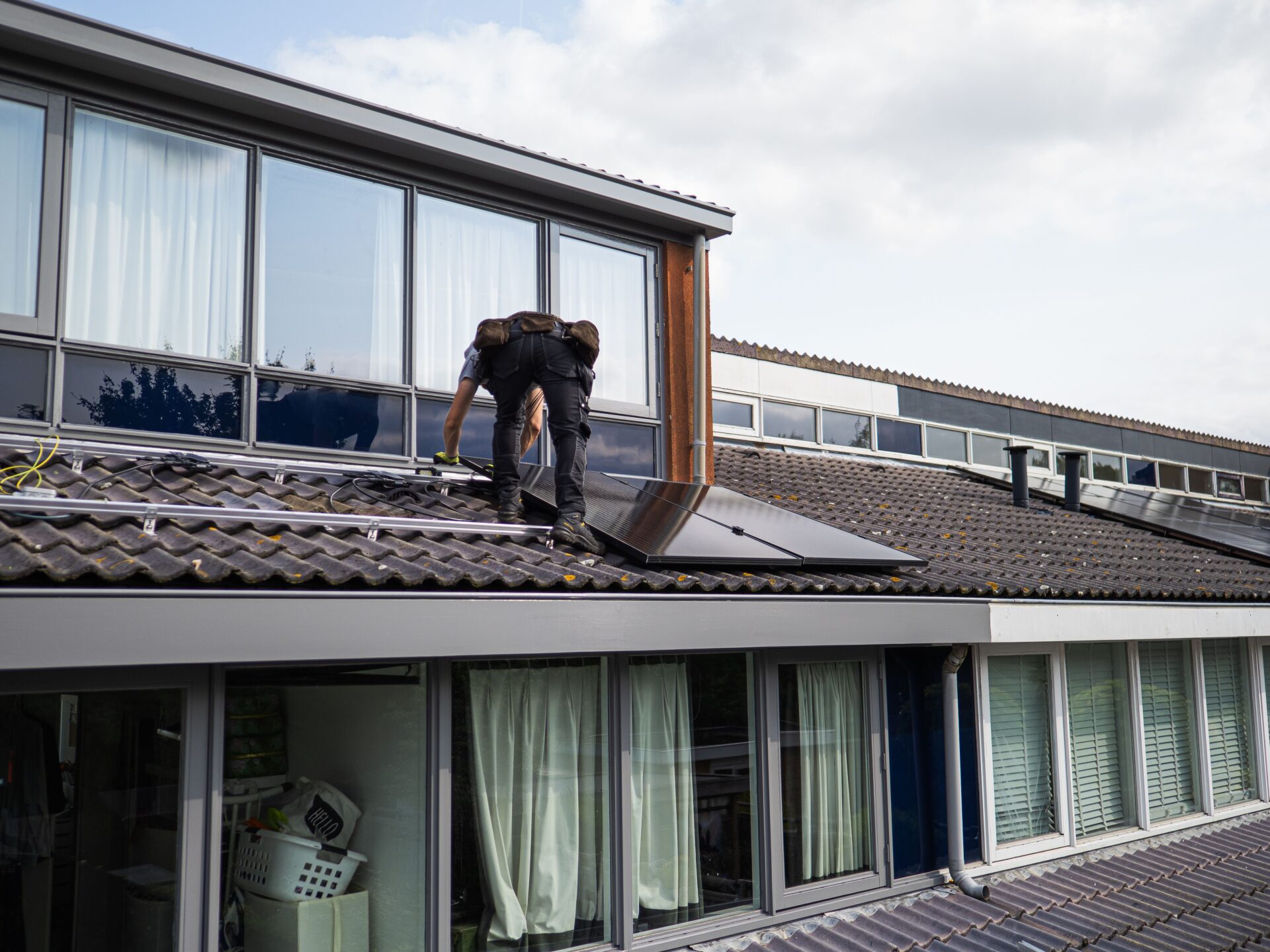 Monteur installiert Solarmodule auf dem Dach eines Gebäudes