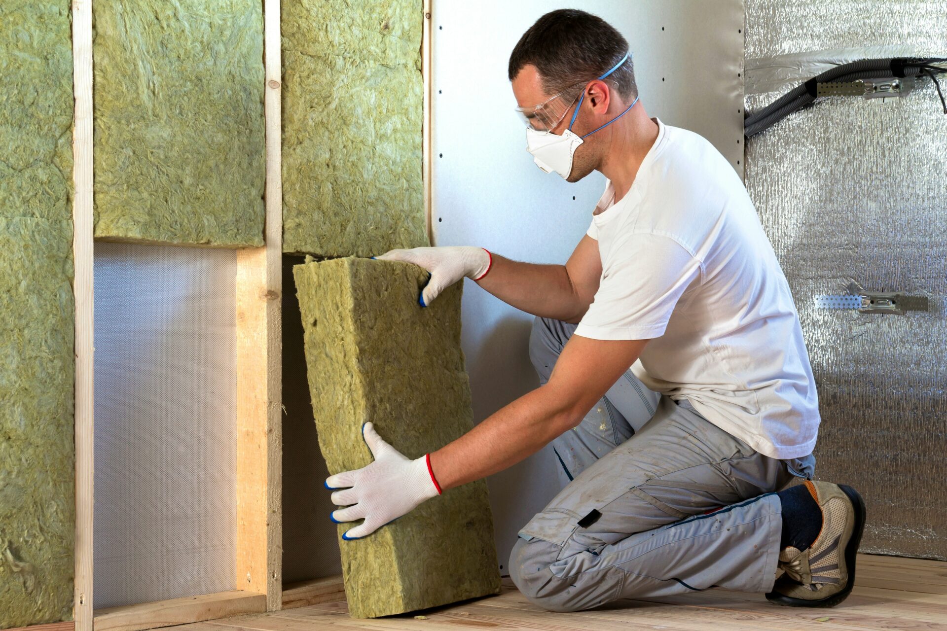 Handwerker bringt Dämmung an einer Wand an