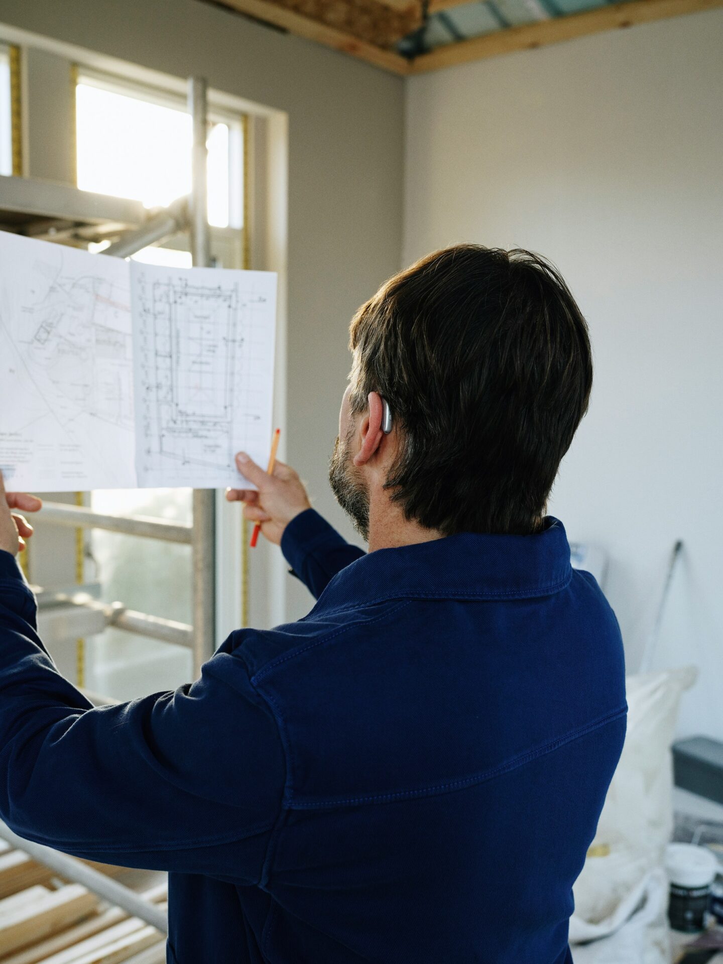 Person prüft einen Bauplan auf einer Baustelle