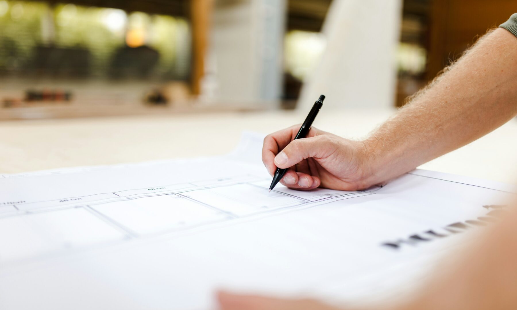 Hand mit Stift auf einem Bauplan