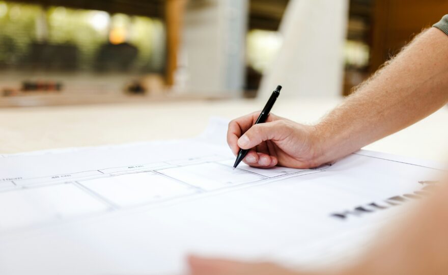 Hand mit Stift auf einem Bauplan