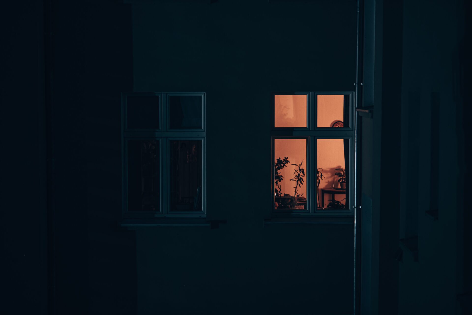 Beleuchtetes Fenster eines Wohnhauses bei Dunkelheit